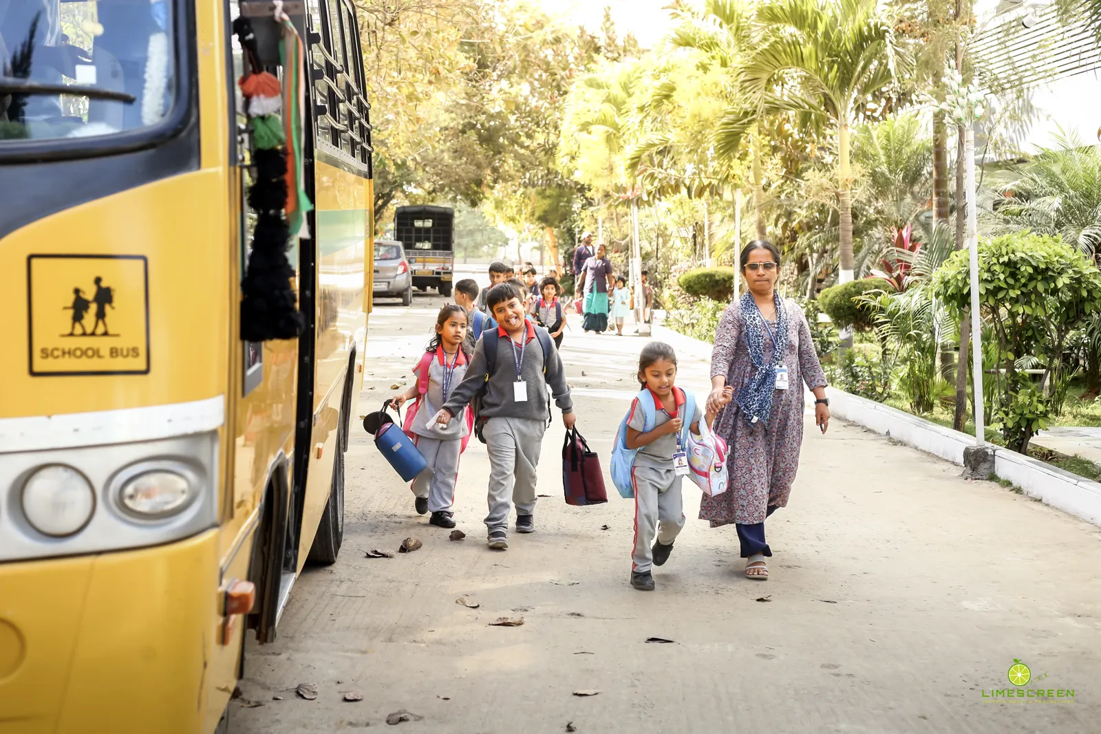 Young students walking from the school bus with a staff member